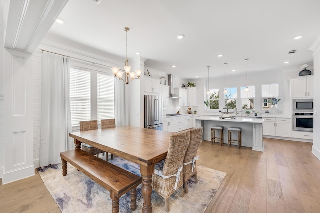 dining area with crown molding, light hardwood / wood-style flooring, a chandelier, and plenty of natural light