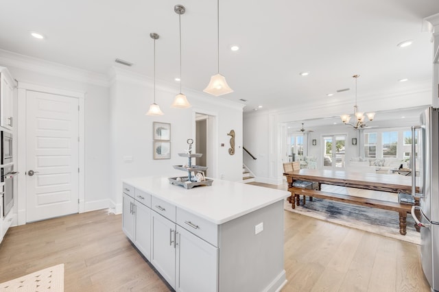 kitchen featuring a center island, hanging light fixtures, ceiling fan with notable chandelier, and appliances with stainless steel finishes