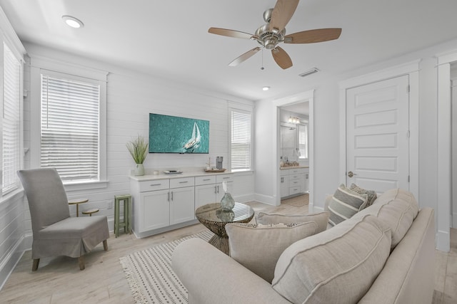 living room with ceiling fan, light hardwood / wood-style floors, and wood walls