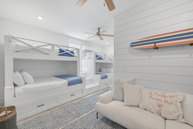 bedroom featuring a wall mounted AC, wood walls, and ceiling fan