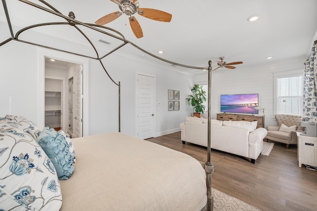 bedroom with a walk in closet, ceiling fan, dark hardwood / wood-style floors, ornamental molding, and a closet