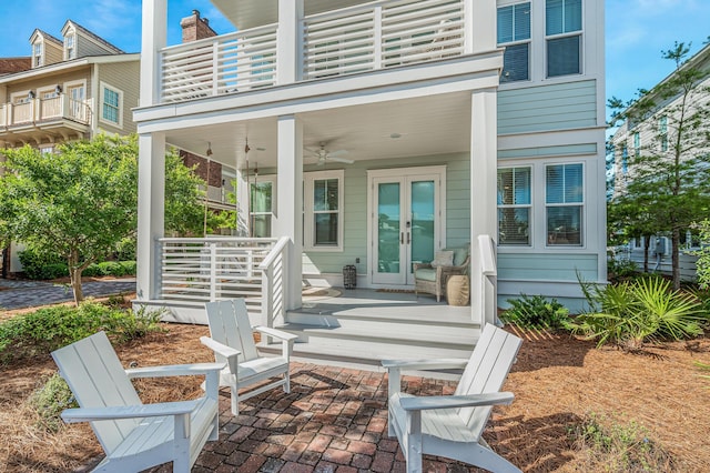 rear view of property featuring a porch, ceiling fan, a balcony, and french doors