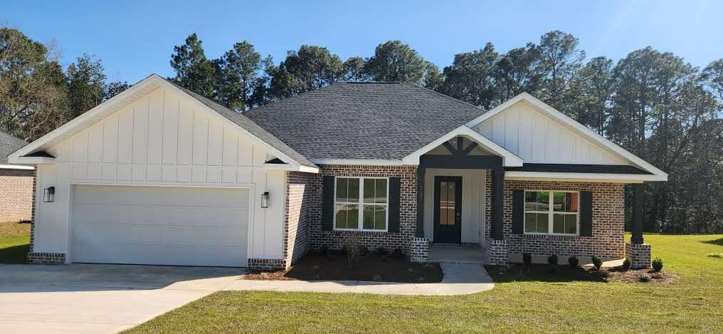 view of front of home featuring a garage, brick siding, board and batten siding, and a front yard