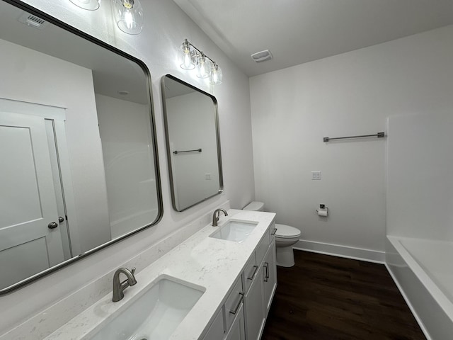 bathroom with baseboards, wood finished floors, toilet, and a sink