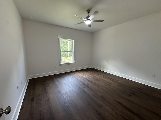 empty room with a ceiling fan, baseboards, and dark wood-type flooring