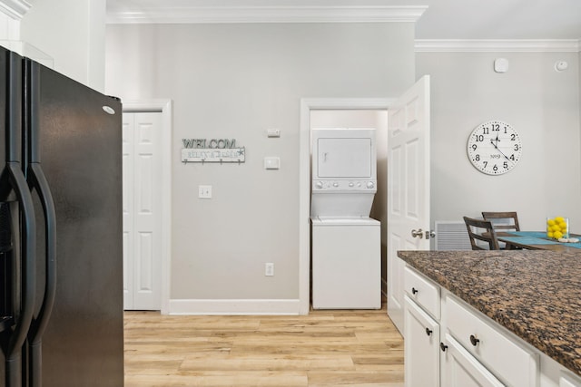 kitchen with black fridge with ice dispenser, stacked washer and dryer, white cabinetry, and dark stone counters