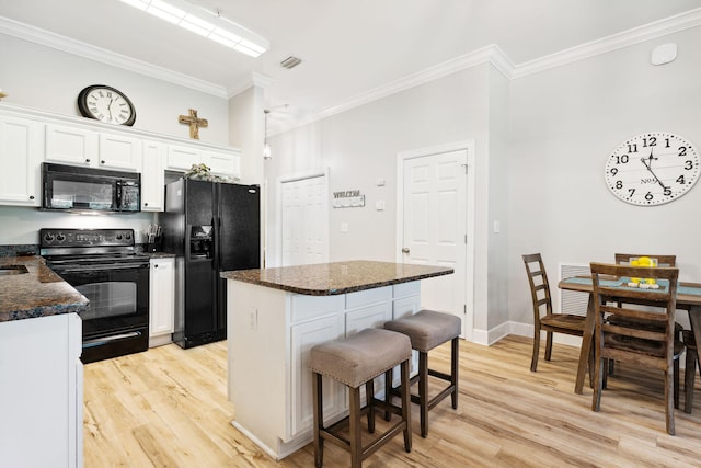 kitchen featuring a breakfast bar, black appliances, white cabinets, light wood-type flooring, and a kitchen island