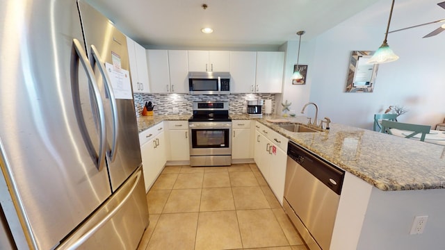 kitchen with kitchen peninsula, appliances with stainless steel finishes, sink, pendant lighting, and white cabinetry