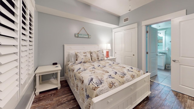 bedroom featuring ensuite bathroom, a closet, and dark wood-type flooring