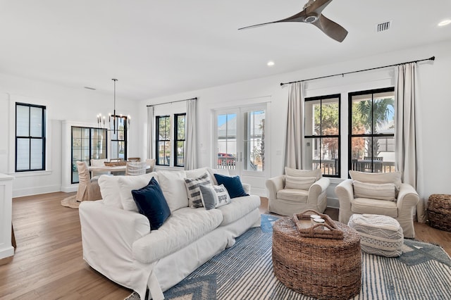 living room featuring a wealth of natural light, light hardwood / wood-style flooring, and ceiling fan with notable chandelier