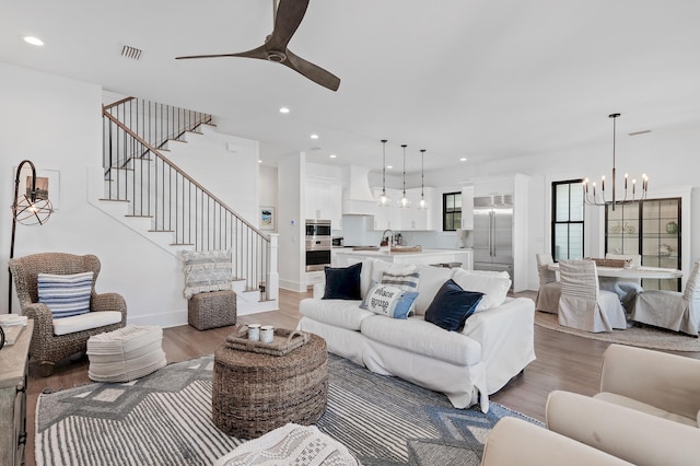 living room with sink, light hardwood / wood-style floors, and ceiling fan with notable chandelier