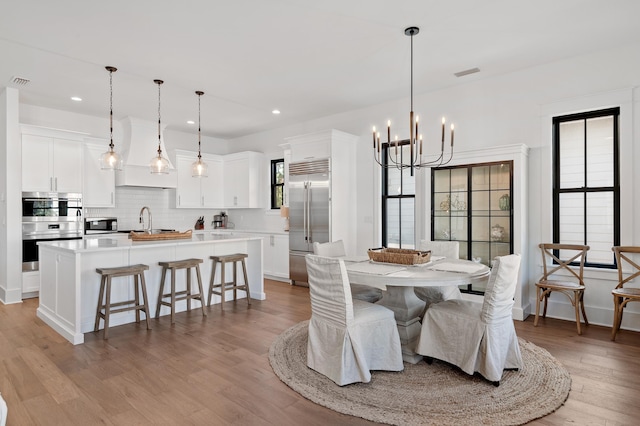 dining area with light hardwood / wood-style floors, sink, and a chandelier