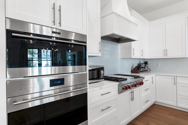 kitchen with white cabinets, custom range hood, appliances with stainless steel finishes, and tasteful backsplash