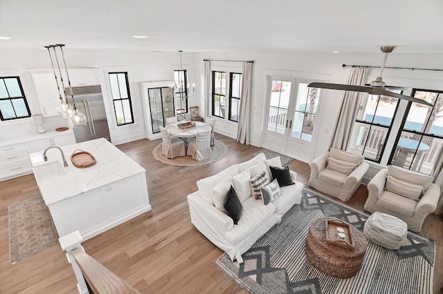 living room featuring light hardwood / wood-style flooring and ceiling fan with notable chandelier