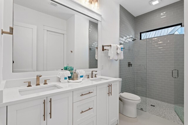 bathroom featuring tile patterned flooring, a shower with door, vanity, and toilet