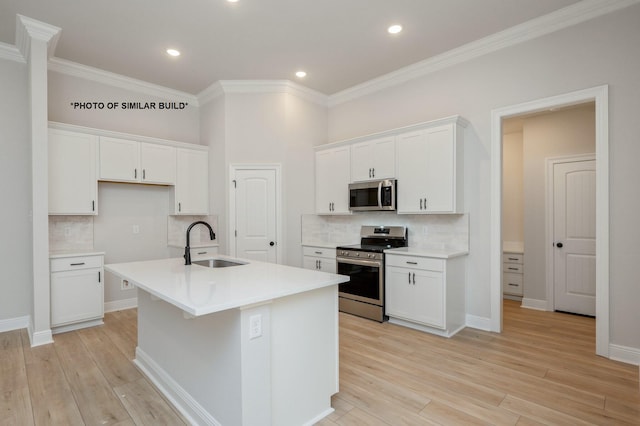 kitchen with stainless steel appliances, a sink, white cabinets, light countertops, and an island with sink