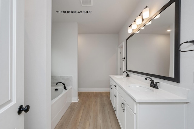 bathroom featuring double vanity, visible vents, a sink, wood finished floors, and a bath