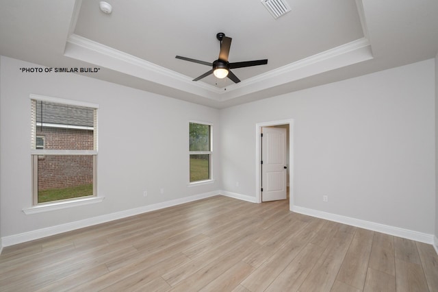 spare room featuring light wood-style flooring, visible vents, a raised ceiling, and baseboards