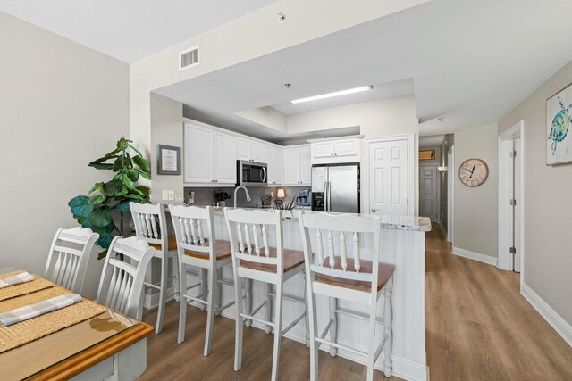 1111 Santa Rosa Blvd Unit 106, Fort Walton Beach, FL 32548 - kitchen with stainless steel appliances, kitchen peninsula, light hardwood / wood-style floors, a breakfast bar area, and white cabinets