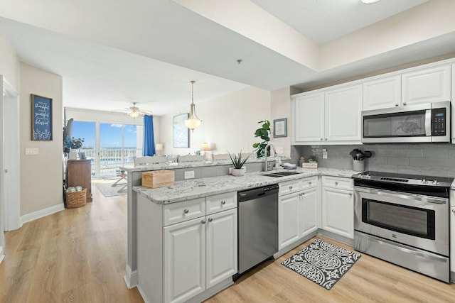 1111 Santa Rosa Blvd Unit 106, Fort Walton Beach, FL 32548 - kitchen featuring kitchen peninsula, white cabinetry, hanging light fixtures, and appliances with stainless steel finishes