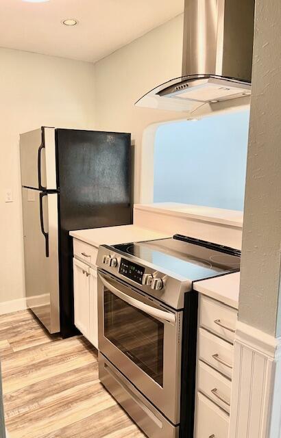 kitchen featuring extractor fan, electric stove, light hardwood / wood-style flooring, white cabinets, and fridge