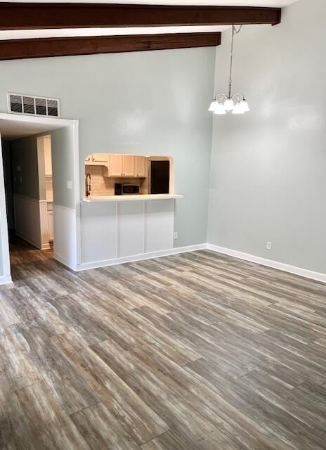 unfurnished living room featuring vaulted ceiling with beams, dark wood-type flooring, and an inviting chandelier