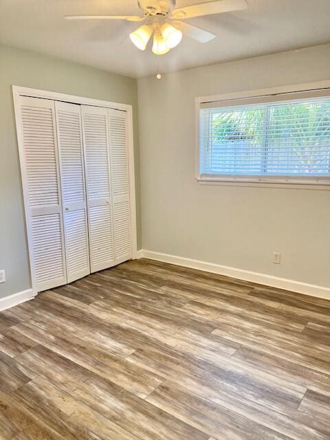 unfurnished bedroom featuring ceiling fan, wood-type flooring, and a closet