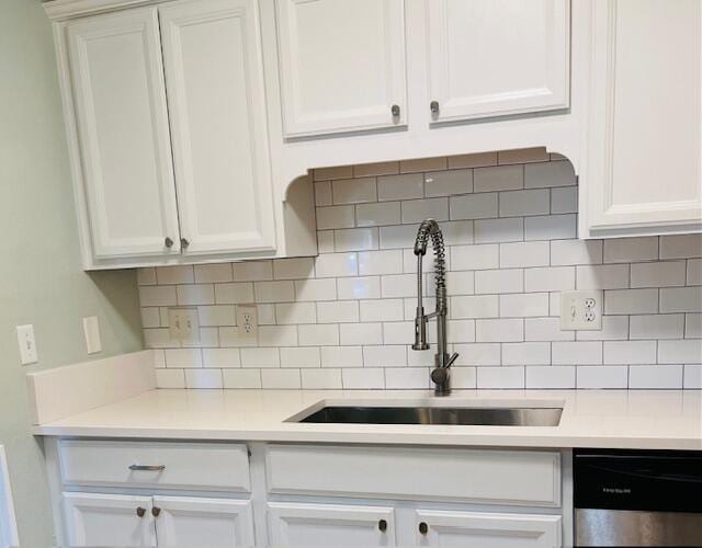 kitchen featuring decorative backsplash, sink, white cabinets, and stainless steel dishwasher