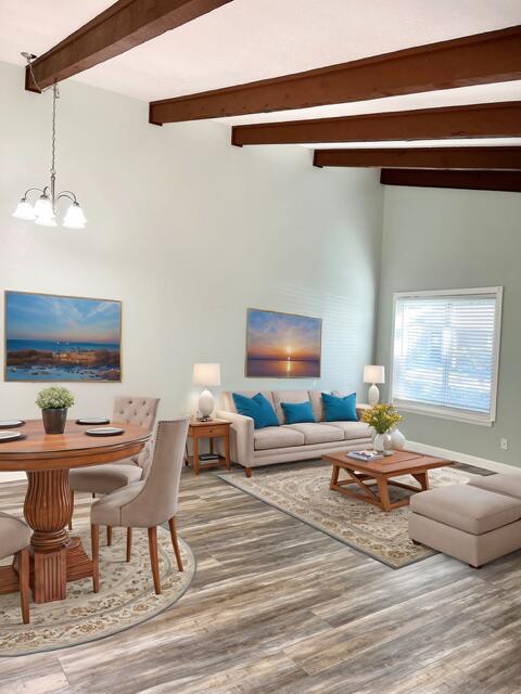 living room with beam ceiling, an inviting chandelier, and hardwood / wood-style floors