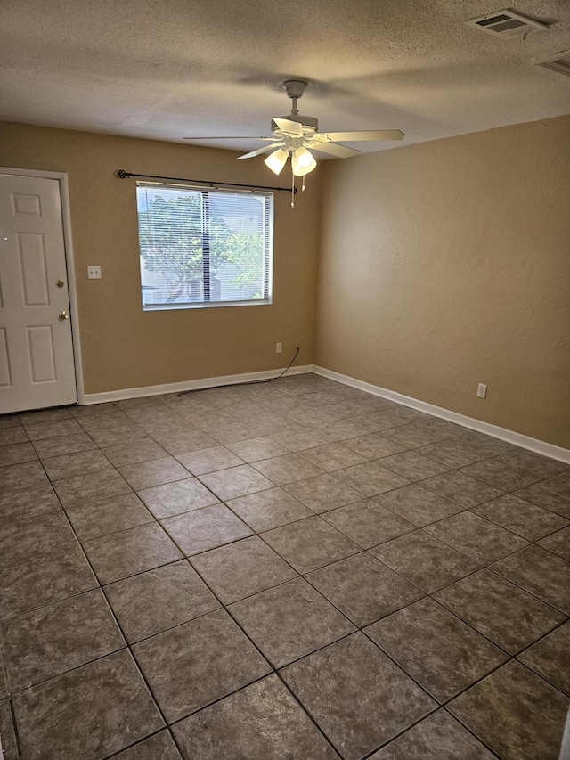 spare room with tile patterned floors, ceiling fan, and a textured ceiling