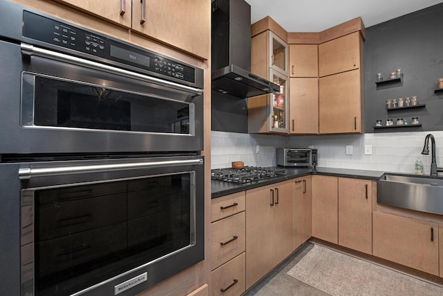 kitchen featuring gas cooktop, backsplash, wall chimney exhaust hood, double oven, and sink