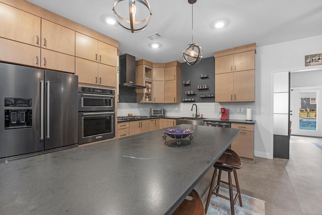 kitchen with pendant lighting, wall chimney range hood, stainless steel appliances, and light brown cabinetry