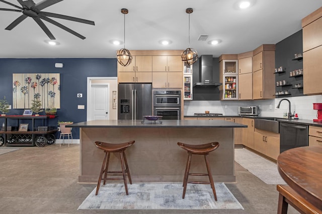 kitchen featuring appliances with stainless steel finishes, a kitchen island, pendant lighting, and wall chimney range hood