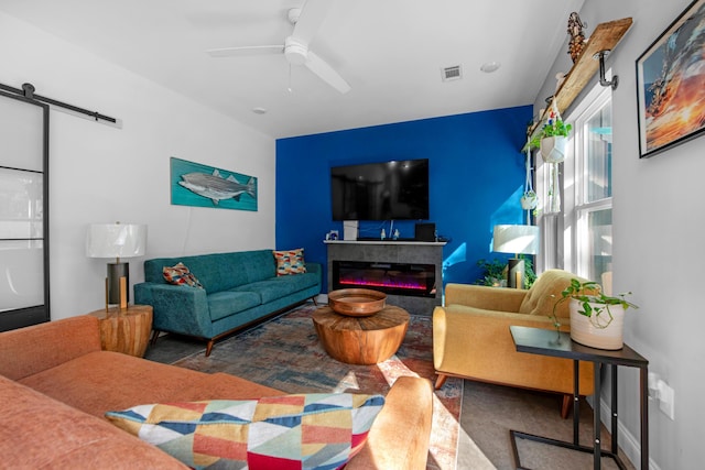 living room with a barn door and ceiling fan