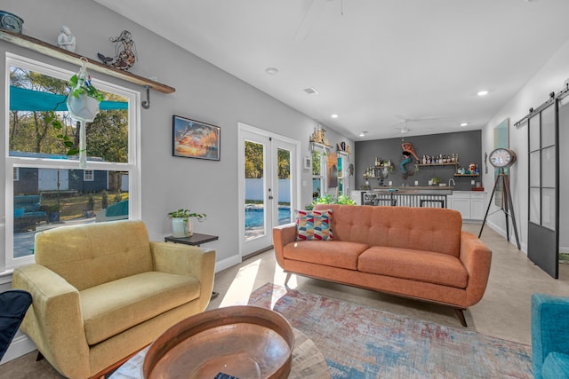 living room featuring french doors, a barn door, ceiling fan, and sink