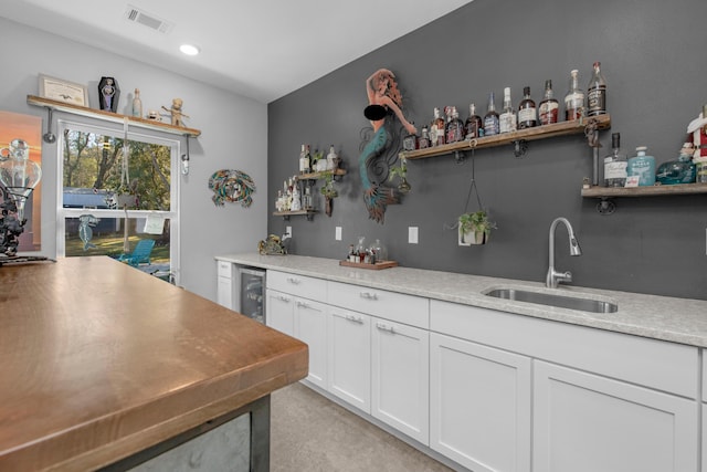 kitchen with white cabinets, beverage cooler, and sink