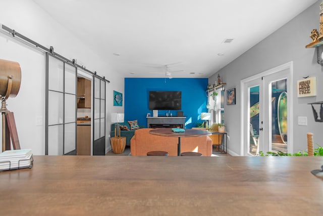 living room featuring a barn door, ceiling fan, and french doors