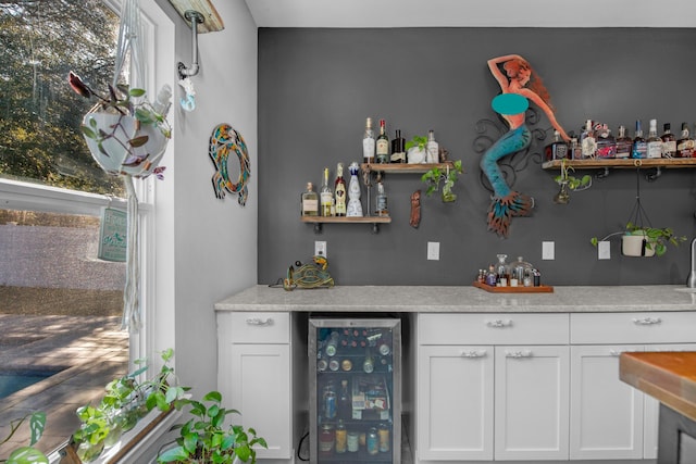 bar with wine cooler and white cabinetry