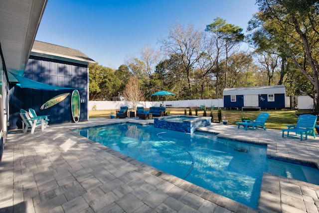 view of pool with a patio area, an in ground hot tub, and an outbuilding