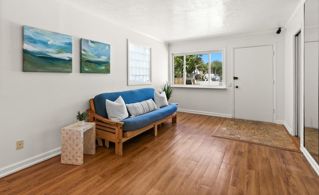 living area with crown molding, baseboards, and light wood finished floors