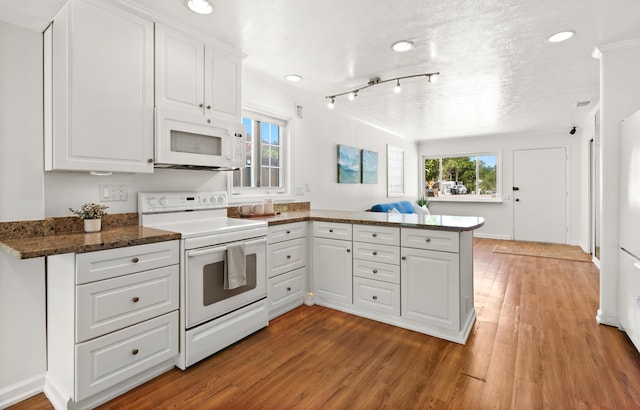 kitchen featuring dark stone counters, white appliances, a peninsula, white cabinets, and light wood finished floors