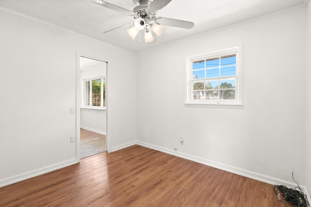 empty room with baseboards, a ceiling fan, wood finished floors, and crown molding