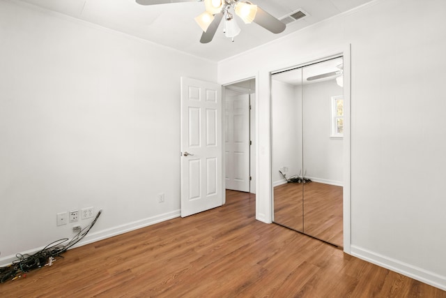 unfurnished bedroom with baseboards, a closet, light wood finished floors, and ornamental molding