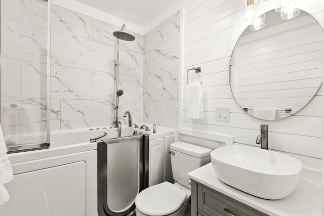 full bathroom featuring vanity, tiled shower / bath combo, washer / dryer, toilet, and wood walls