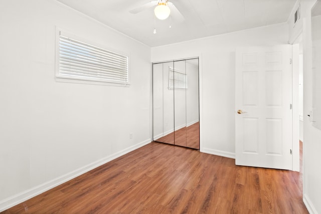 unfurnished bedroom with hardwood / wood-style floors, ceiling fan, crown molding, and a closet