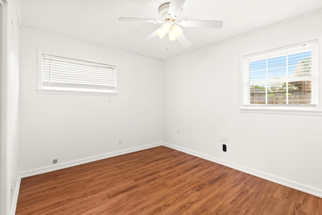 empty room featuring a ceiling fan, crown molding, baseboards, and wood finished floors