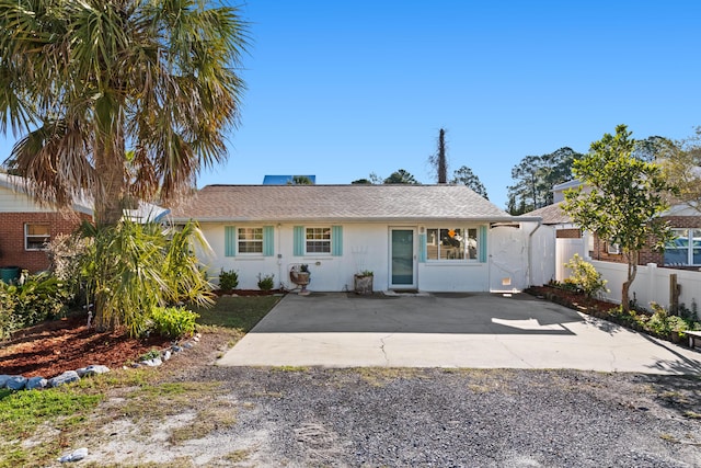 view of front of home with a shingled roof, concrete driveway, fence, and stucco siding