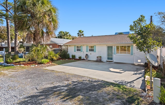 ranch-style home featuring stucco siding, driveway, a patio, and roof with shingles