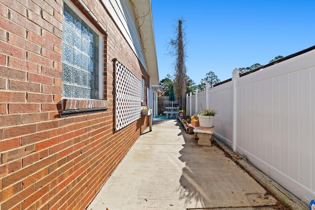 view of side of home with fence and brick siding