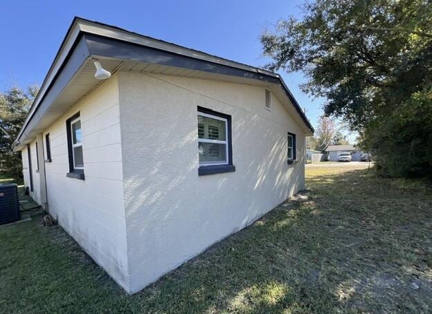 view of side of property with a lawn and cooling unit